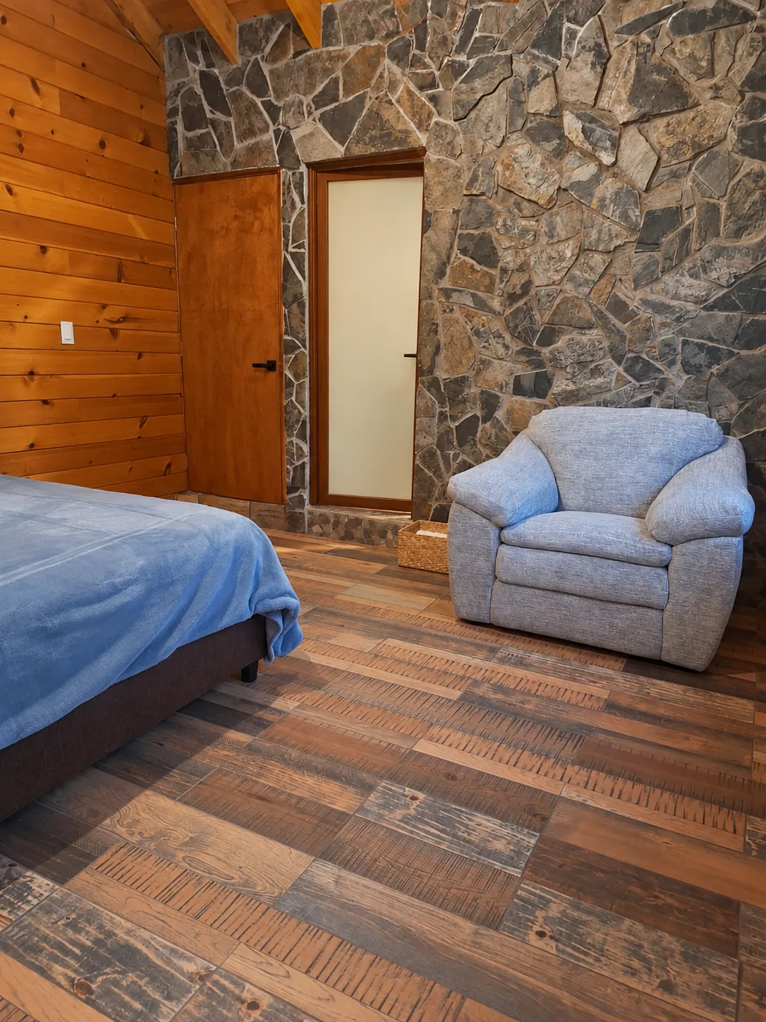 Sala rústica acogedora con piedra, madera y sillón